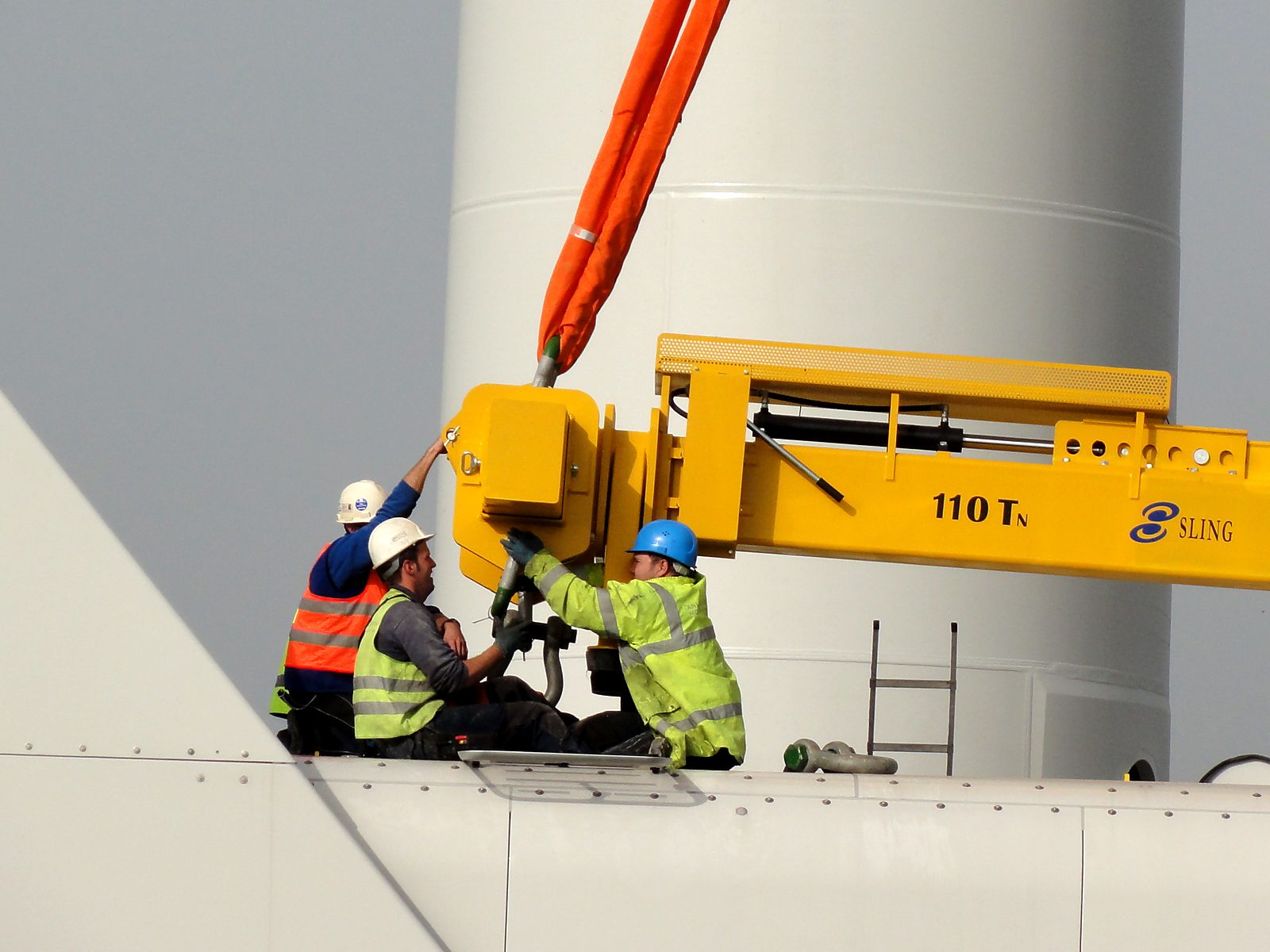 Installation crew in hard hats and hi-vis rigging the nacelle lifting yoke at Balchik Wind I