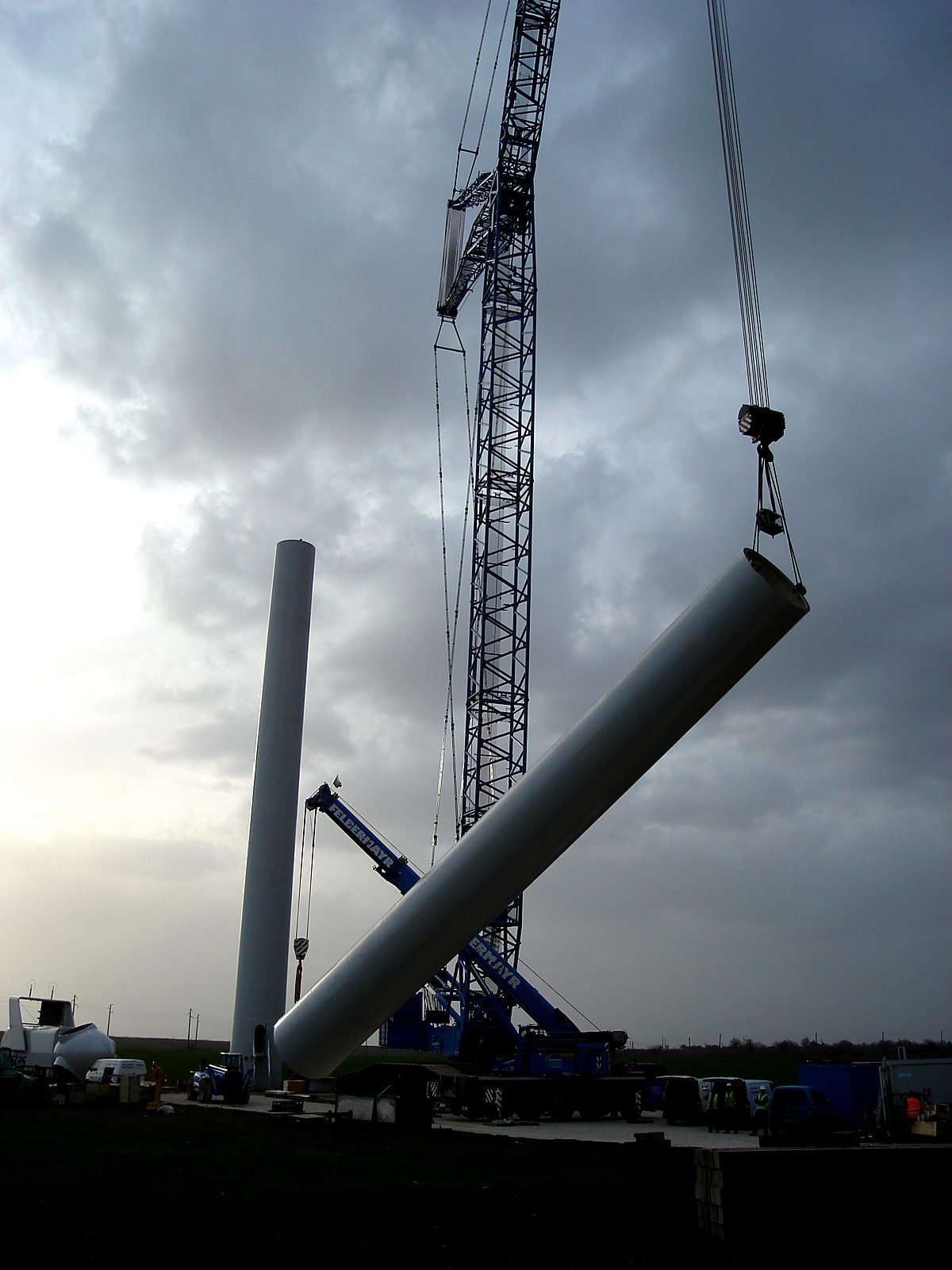 Crane raising a tower section under storm clouds at Balchik Wind I