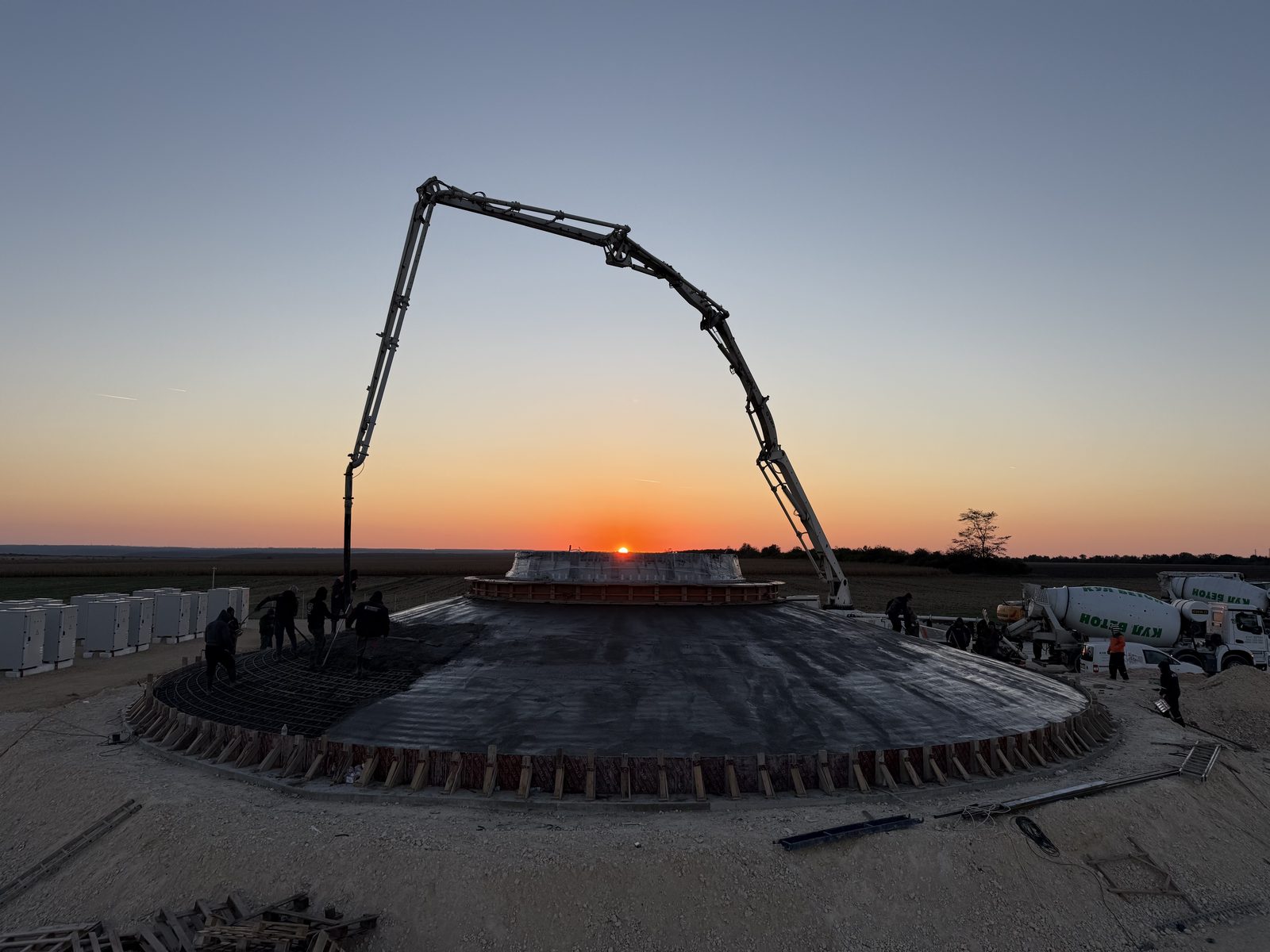 Concrete pump over the Balchik Wind IV foundation as the sun sits on the horizon
